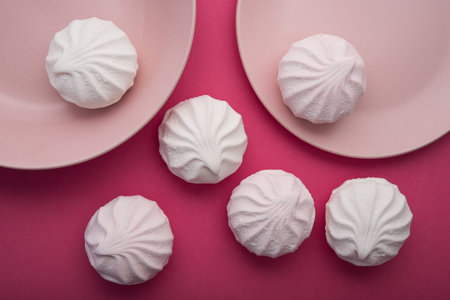 Tasty sweet zephyr on a white plate and pastel pink background. 