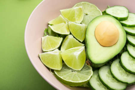 healthy food salad with avocado, lime and cucumber on a green background. Nutrition organic mealの写真素材