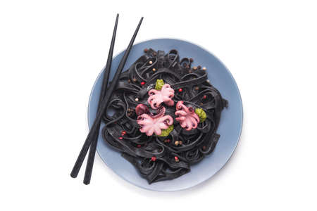 Italian black pasta with cuttlefish ink and marinated octopus on a plate isolated on white. Tasty asian seafood. Top viewの写真素材