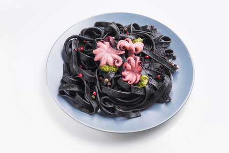 Italian black pasta with cuttlefish ink and marinated octopus on a plate isolated on white. Tasty asian seafood.の写真素材