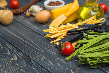 three varieties of raw tagliatelle pasta, classic, spinach and cuttlefish on a wooden table. Italian cooking dinner.の写真素材