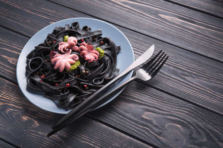 Italian black pasta with cuttlefish ink and marinated octopus on a table. Tasty asian seafood.の写真素材