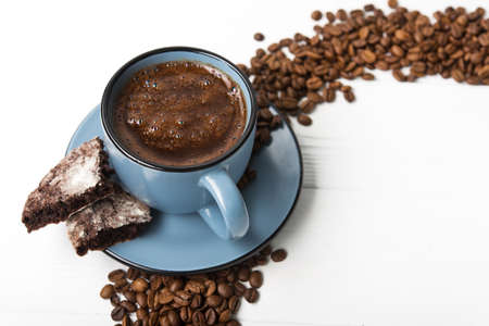 Blue coffee cup with chocolate cookie on a white wooden tableの写真素材