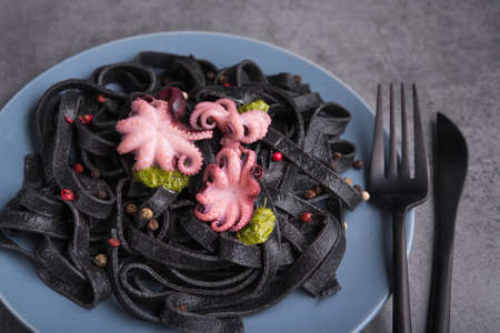 Italian black pasta with cuttlefish ink and marinated octopus on a plate, stone table. Tasty asian seafood.の写真素材