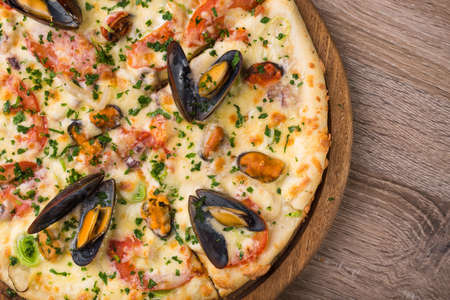 Seafood Italian Pizza with mussles and squid on a wooden board. top view fastfoodの写真素材