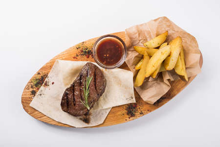 Beef steak with fried potatoes on a wooden board isolated on a white backgroundの写真素材