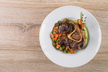 beef stew with vegetables, spices and garlic on a white plate. Impressive meals at the restaurantの写真素材