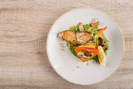 steak fish escolaar with vegetables and cashew nuts on a white plate. Beautiful restaurant serving dishesの写真素材