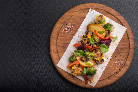 Grilled vegetables, mushrooms, basil, pepper, garlic and corn on a wood boardの写真素材