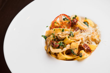 delicious pasta with chicken and tomato on a white plate, black backgroundの写真素材