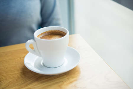 Americano coffee cup with milk on a wooden table in cafe near the windowの写真素材