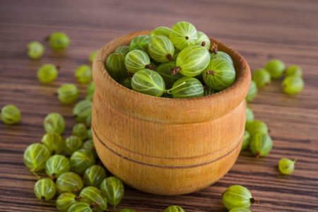 green fresh gooseberry berry in a bowl on wooden table. ripe fruit foodの写真素材