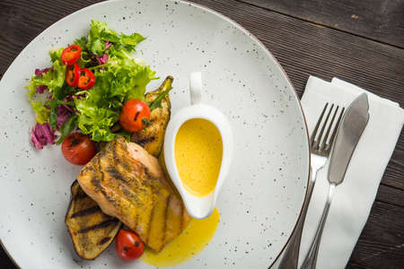 yummy fish steak with vegetables and sauce on a white plate. top viewの写真素材