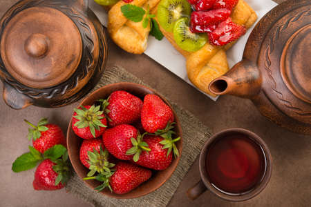 Fruit tea and sweet bakery with strawberry, kiwi in sugar glaze. Summer dessert food. Top view.の写真素材