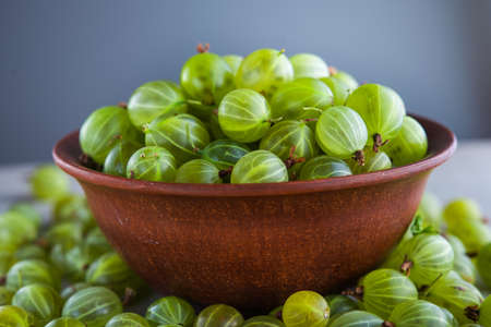 green fresh gooseberry berry in a bowl on wooden table. ripe fruit foodの写真素材