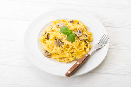 Tagliatelle pasta with cheese and mushrooms on a white wooden table. italian foodの写真素材