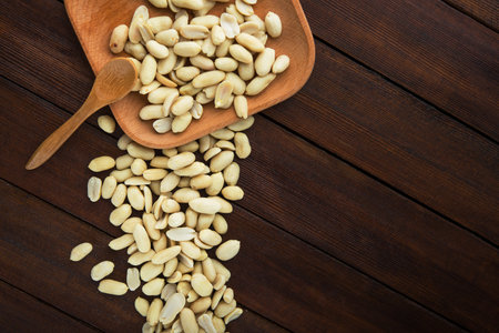 Peeled peanuts on a wooden plate, top view.