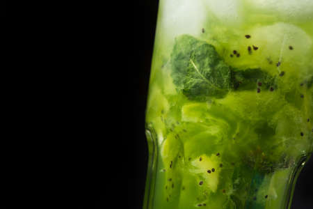 closeup mojito cocktail with ice and mint leaf , kiwi grains, on a black backgroundの写真素材