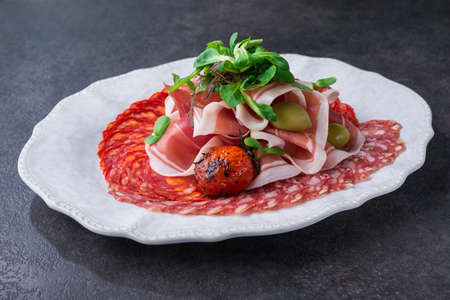 cold cuts with salami, sausage and prosciutto on a white plateの写真素材