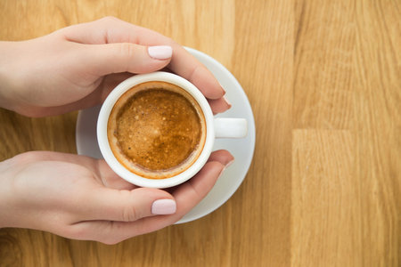 Blonde woman with white coffee cup sits in a cafe near the window. Lunch break background. top view