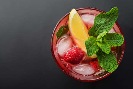 Cold raspberry mojito cocktail with ice and mint leaf on a black backgroundの写真素材