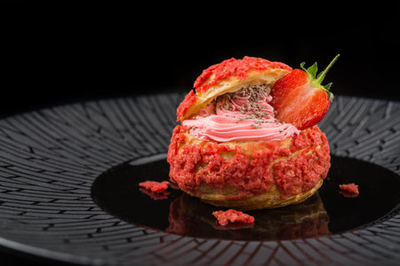 Sweet french dessert cream puff with strawberry on a black background