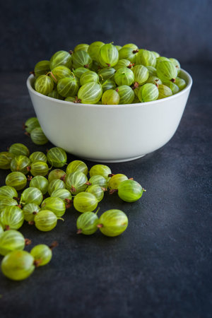 sweet fresh gooseberry berry in a bowl on dark stone background