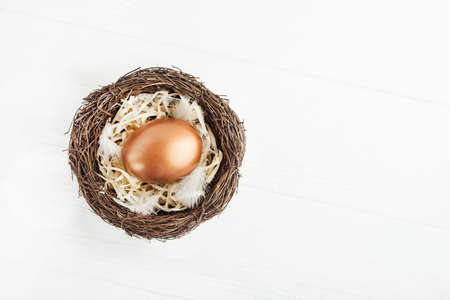 Golden eggs in the nest on a white wooden table. success concept background. top viewの写真素材