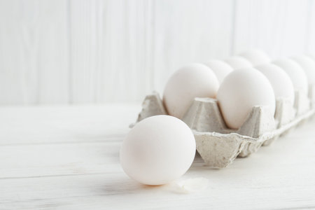 raw white eggs in the tray on a wooden table