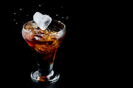 Cold glass with whiskey on a black background. Dark alcohol beverage.の写真素材