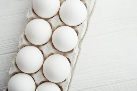 raw white eggs in the tray on a wooden table. top view