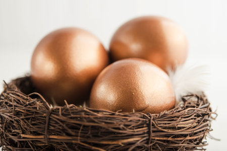 Golden eggs in the nest on a white wooden table. success concept background