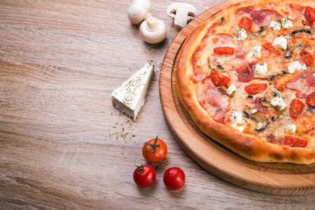 Hot italian pizza with bacon, mushroom and cheese on wooden board.の写真素材