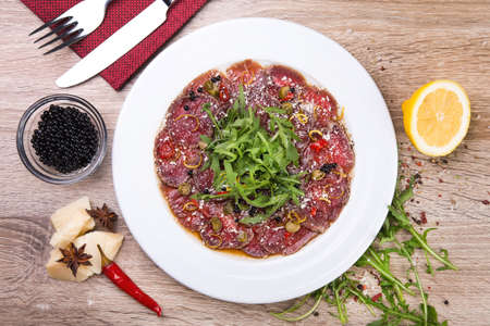 beef carpaccio with arugula and black caviar on wooden table. top view. flat layの写真素材