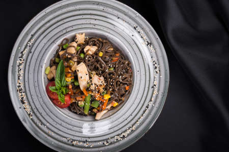 Wok pasta with meat, vegetables, asparagus and pepper on a black table. Asian food lunch. view from aboveの写真素材