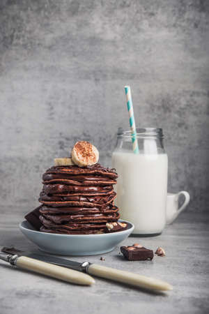 Tasty pancake with chocolate, banana and milk bottle on a stone table. Dessert high-calorie breakfast.の写真素材