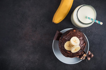 Sweet chocolate pancake with banana on a stone background. high-calorie breakfast. junk food. view from aboveの写真素材
