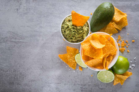 Bowl with guacamole sauce and nachos chips on a stoneの写真素材