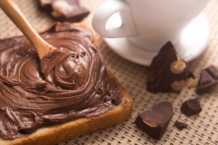 Sweet breakfast of bread with chocolate spread and a cup of coffee on the morning table