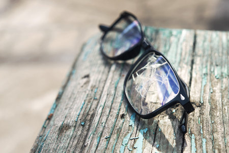 Black broken glasses lie on the bench in an unfavorable cityの写真素材