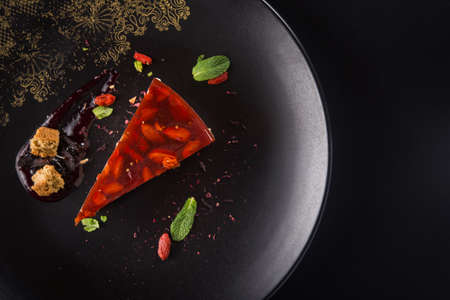 Sweet goji berry cheesecake with mint leaves on a black plate. Popular and trend food. top view, copy spaceの写真素材