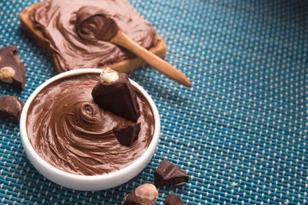 Bowl with tasty melted chocolate on a blue wooden tableの写真素材