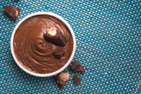 Bowl with tasty melted chocolate on a blue wooden table