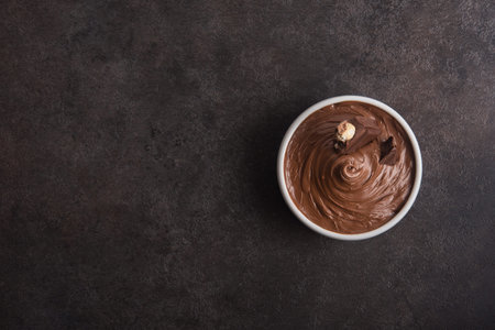 Sweet chocolate cream with bars and nuts on a stone table. Dessert homemade ingredient. Top view,...