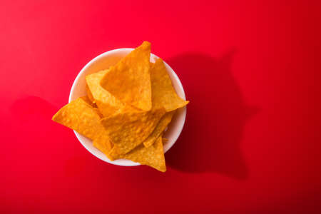 Golden nacho chips in bowl on a redの写真素材