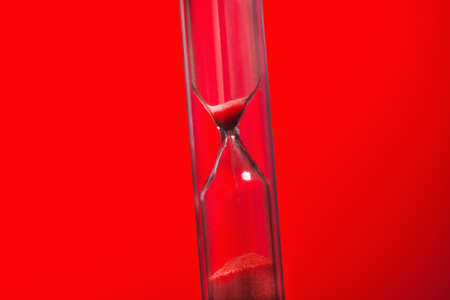 Bright colored time with hourglass on a redの写真素材