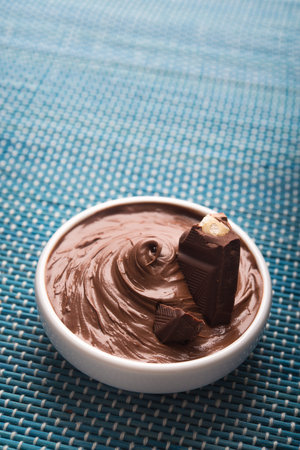 Bowl with tasty melted chocolate on a blue wooden table