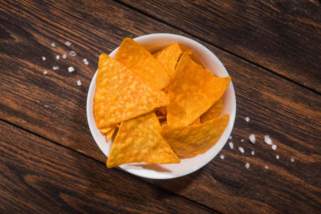 mexican nacho chips in a bowl on a wooden table.の写真素材