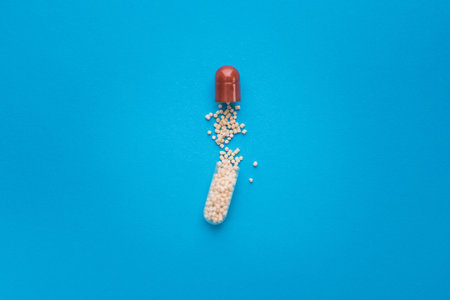 Closeup of open medical capsule pill on a blue background. top view