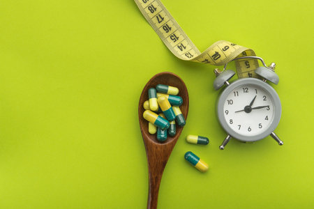 Time for diet and pill treatment on a green background. Diet concept and excess weight. Top or above...